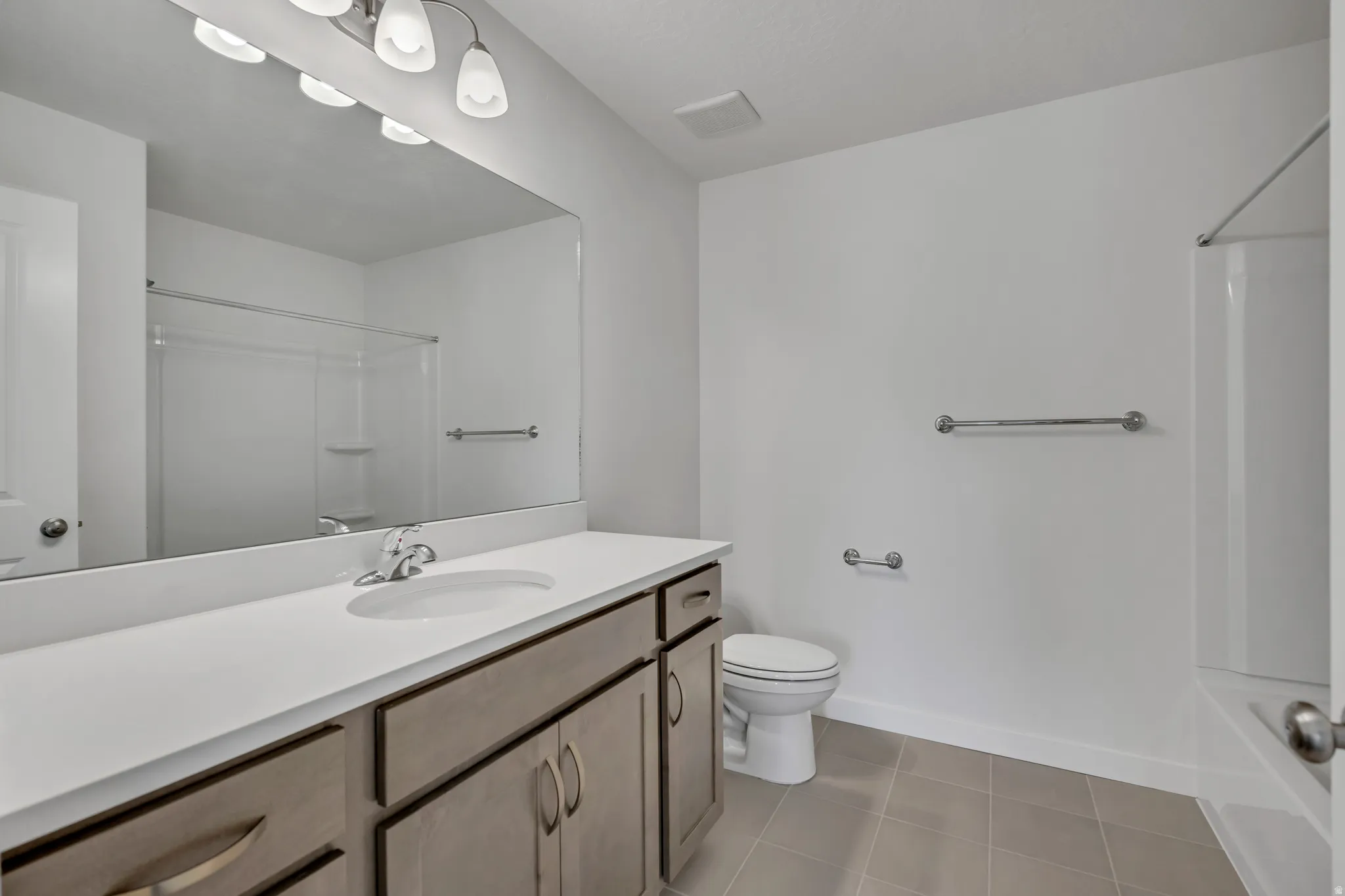 Bathroom with vanity, washtub / shower combination, and light tile patterned floors