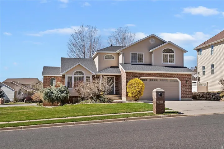 Traditional-style home featuring brick siding, a garage, a front yard, and driveway