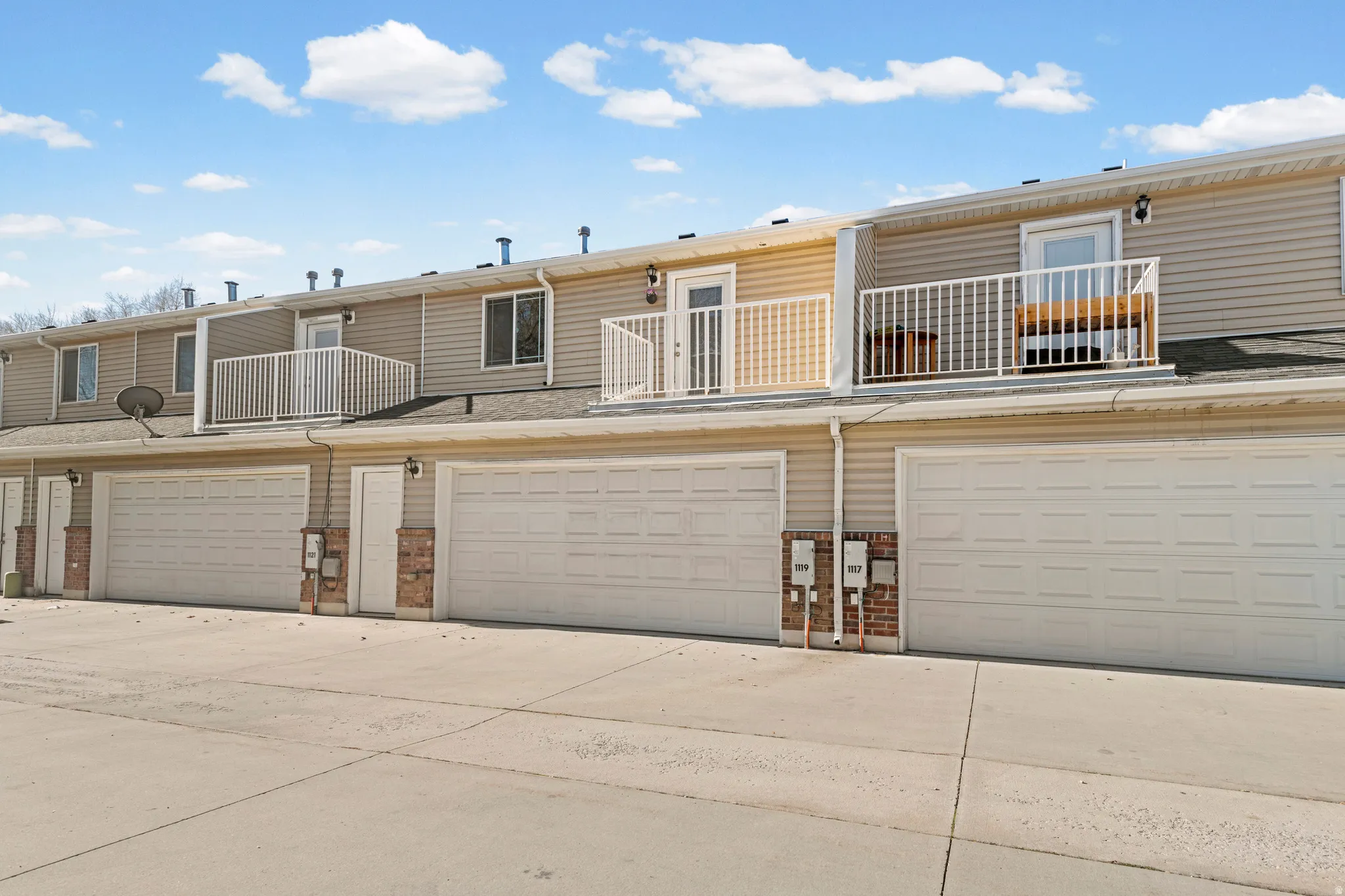 Rear view of house with a balcony, concrete driveway, brick siding, and a garage