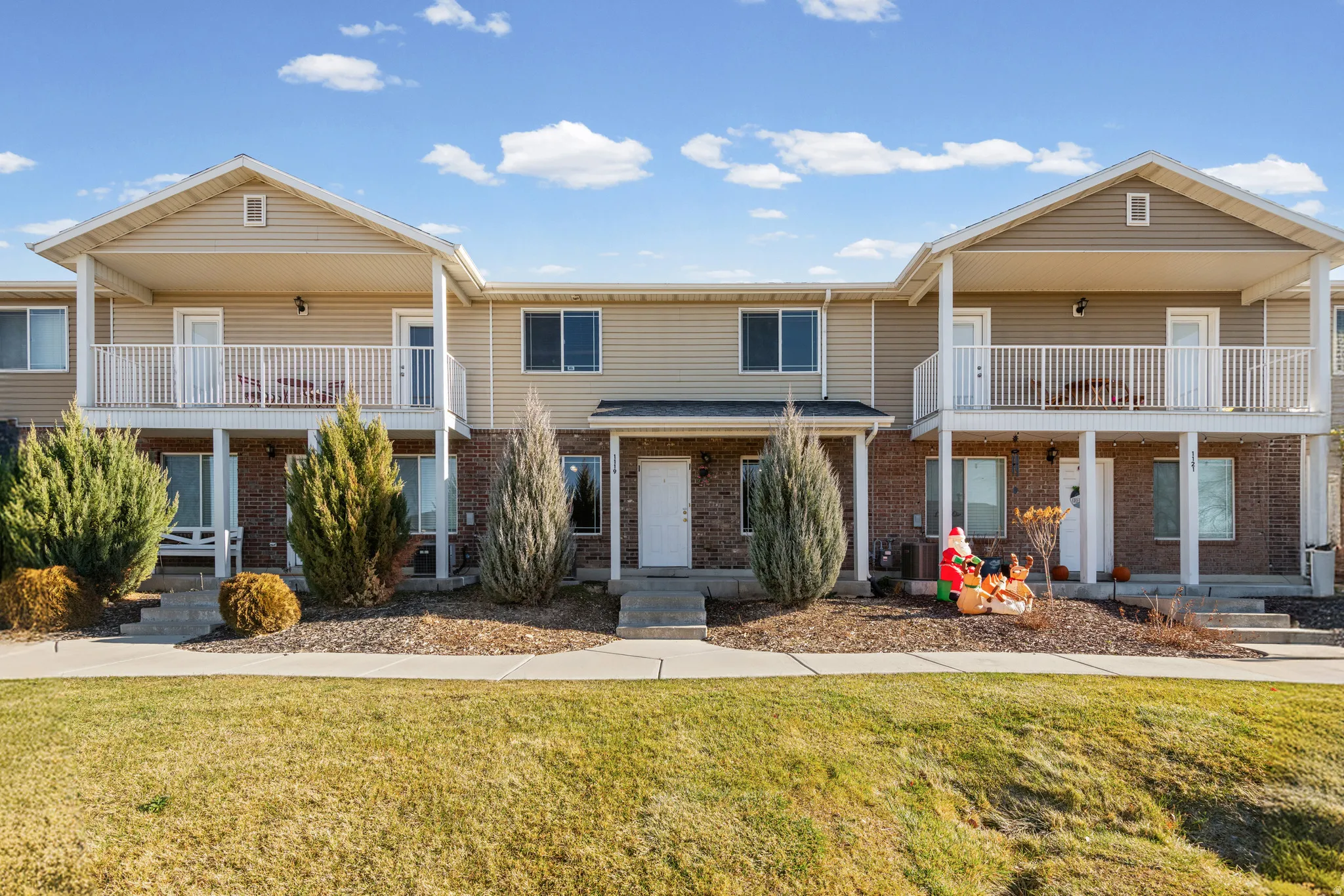 Traditional home with brick siding, a balcony, a front yard, and covered porch