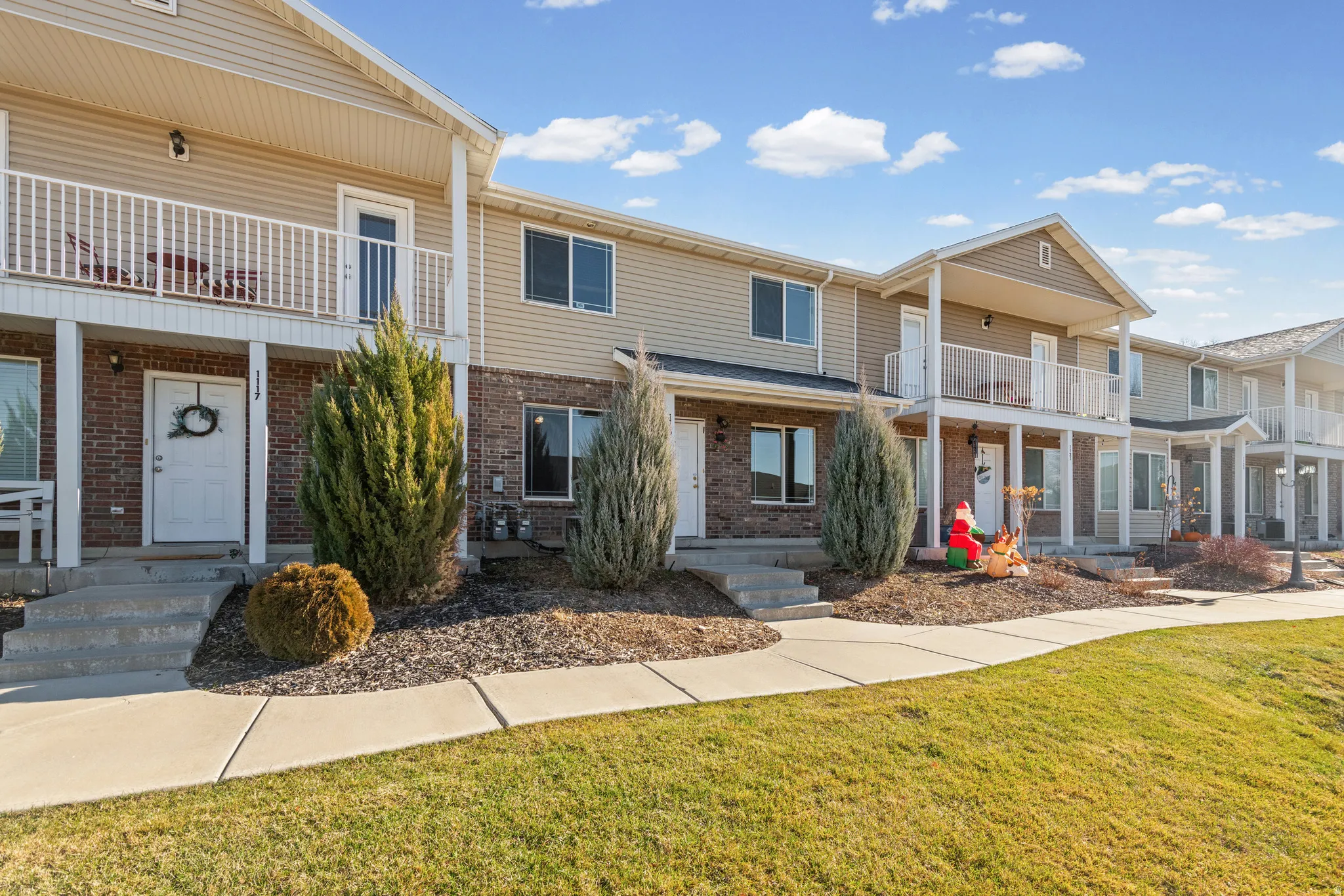 Traditional-style home featuring a balcony, brick siding, and a front lawn
