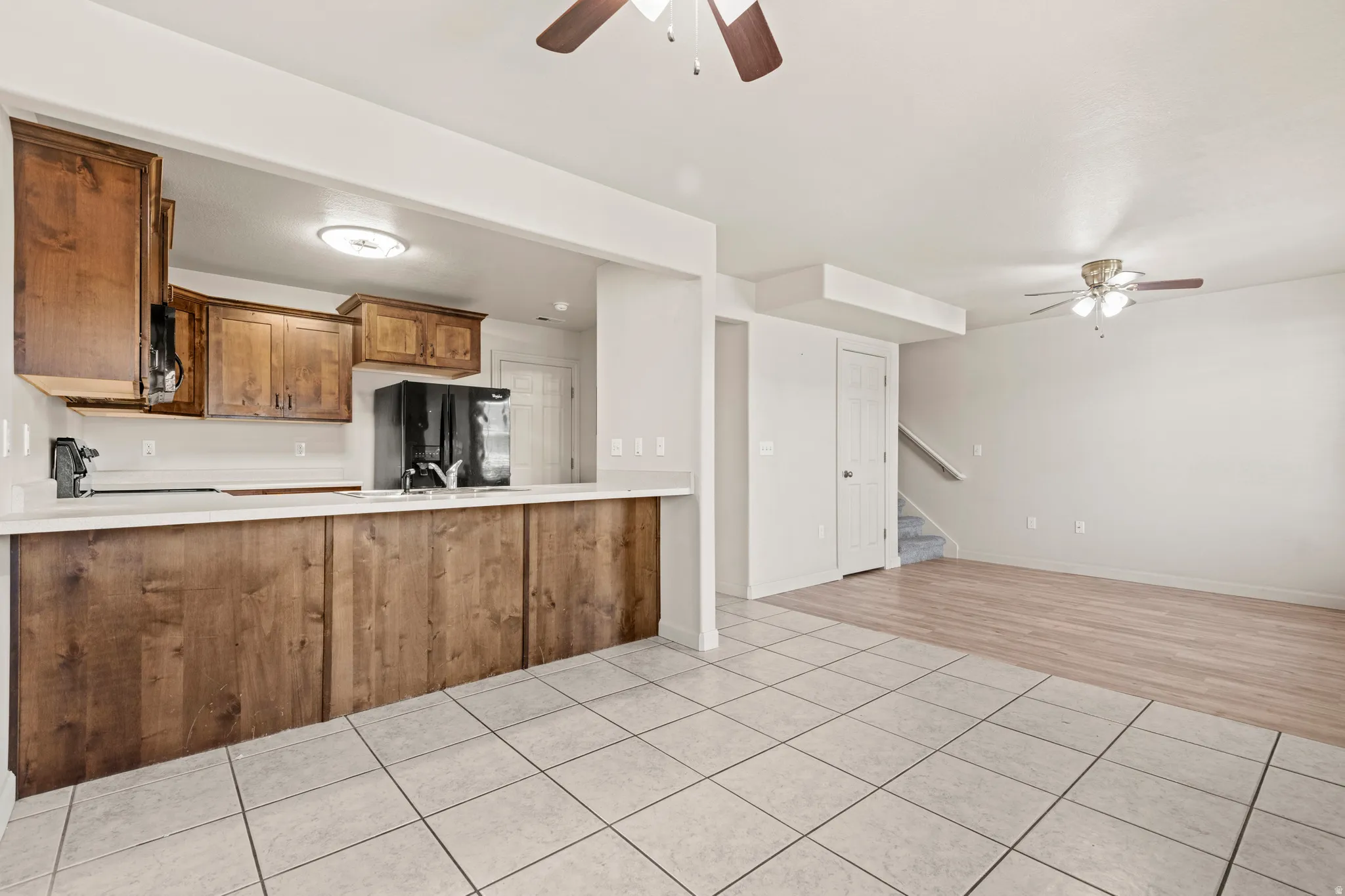 Kitchen with a ceiling fan, wood finish cabinetry, light countertops, and light tile patterned floors