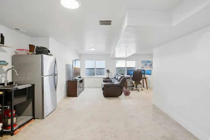 Kitchen with freestanding refrigerator, a desk, light carpet, and open floor plan