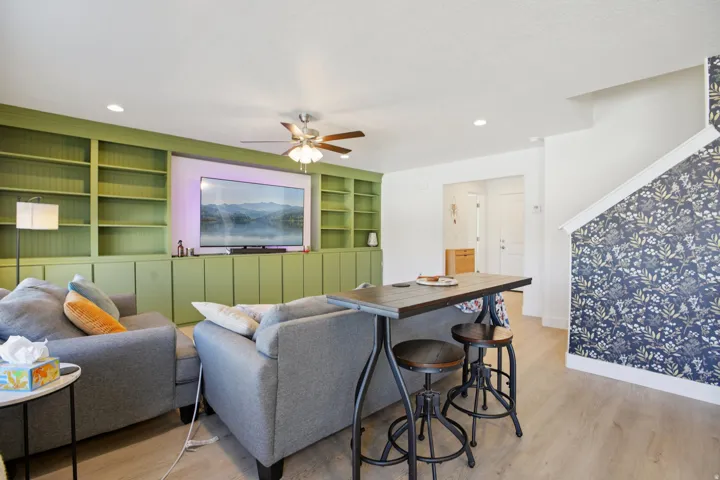 Living room featuring built in features, light wood-style floors, a ceiling fan, and recessed lighting