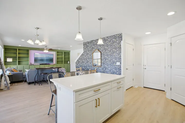 Kitchen featuring wallpapered walls, a breakfast bar area, a center island, white cabinetry, and built in shelves