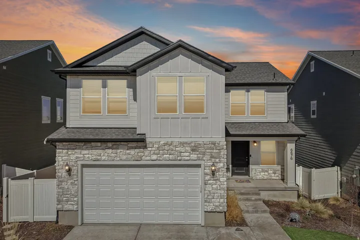 View of front of house featuring stone siding, board and batten siding, driveway, and covered porch