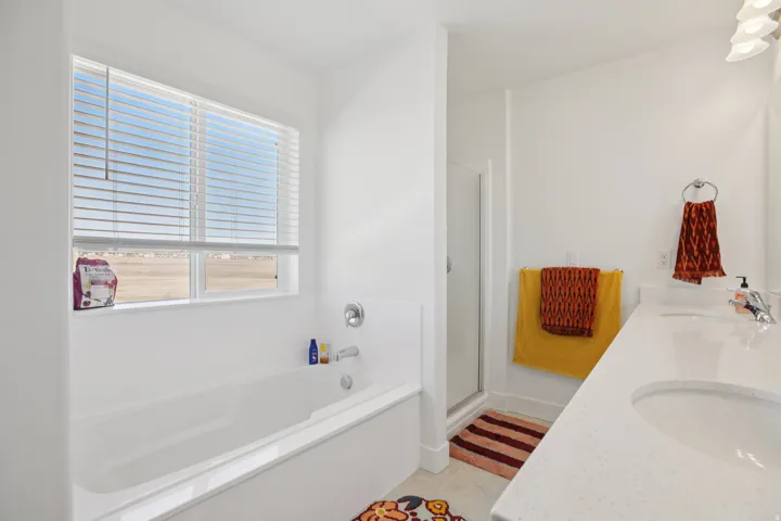 Full bathroom featuring double vanity, a stall shower, light tile patterned floors, and a bath