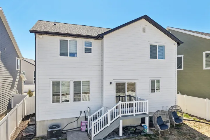 Back of property featuring a fenced backyard, roof with shingles, and a patio