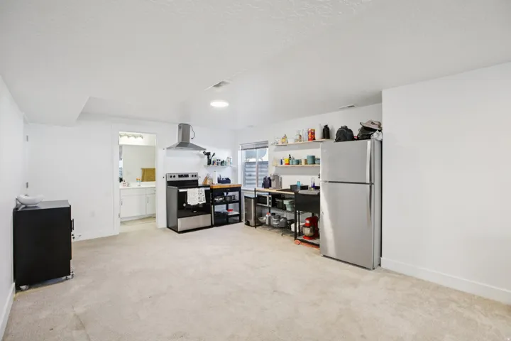 Kitchen with freestanding refrigerator, electric stove, light colored carpet, and a textured ceiling