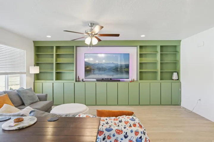 Living room featuring built in features, wood finished floors, ceiling fan, a textured ceiling, and recessed lighting
