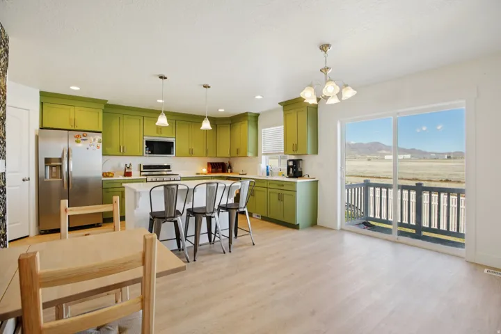 Kitchen with green cabinets, stainless steel appliances, a chandelier, a breakfast bar, and a mountain view