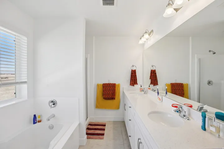 Full bath featuring double vanity, a bath, healthy amount of natural light, and a shower stall