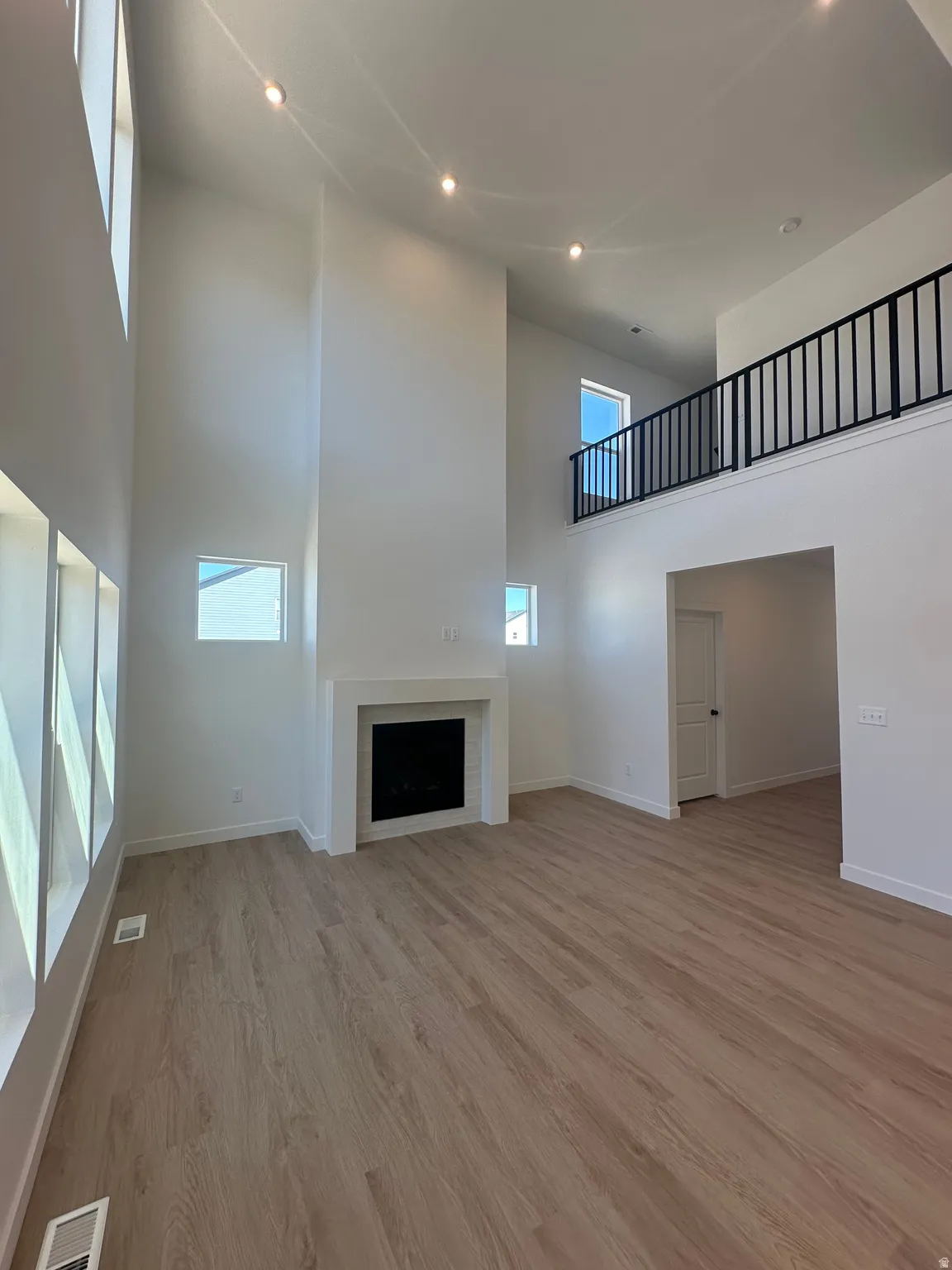 Unfurnished living room with a high ceiling, light wood-type flooring, a fireplace, and recessed lighting