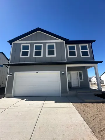 Traditional-style home featuring board and batten siding, an attached garage, driveway, and covered porch
