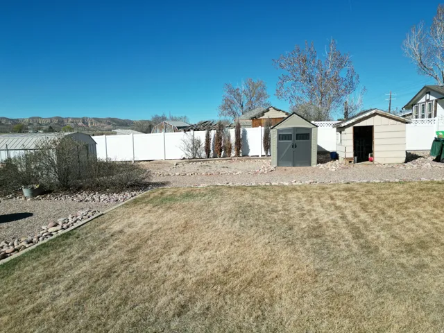 Fenced backyard featuring a shed