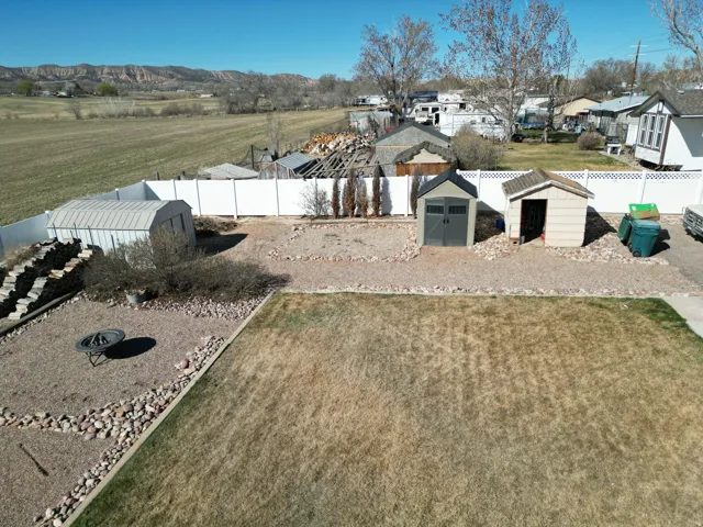 Fenced backyard featuring sheds and a residential view