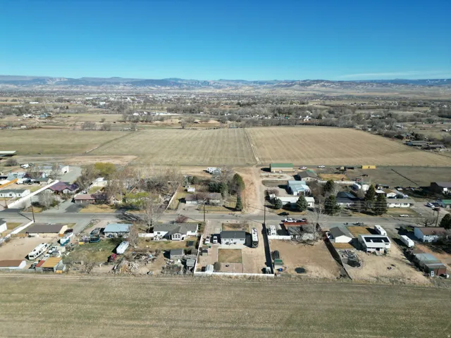 Aerial overview of property's location with rural landscape, mountains, and rows of crops-looking north