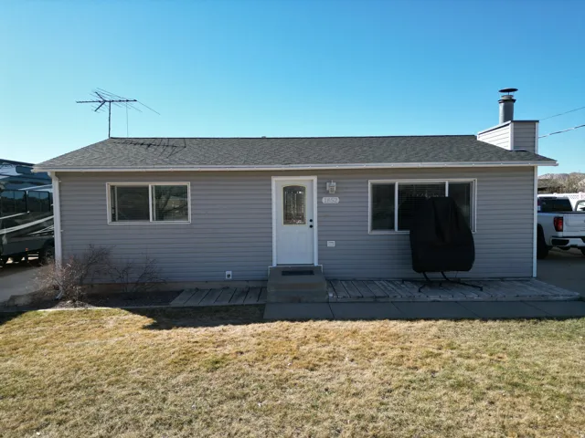 View of front of house featuring a front yard, a chimney, roof with shingles, and entry steps
