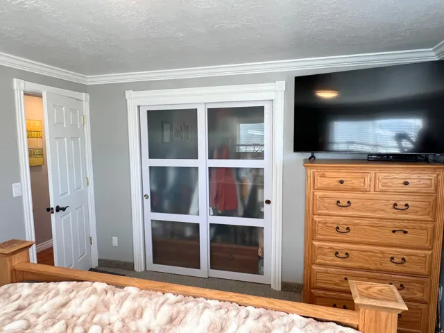 Bedroom with a closet, a textured ceiling, and ornamental molding