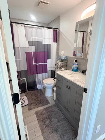 Full bathroom with vanity, curtained shower, a textured ceiling, and light wood-style floors