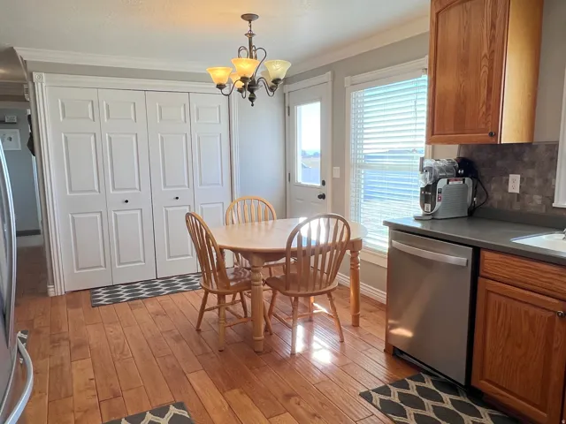 Dining area with light wood-type flooring, a chandelier, and crown molding