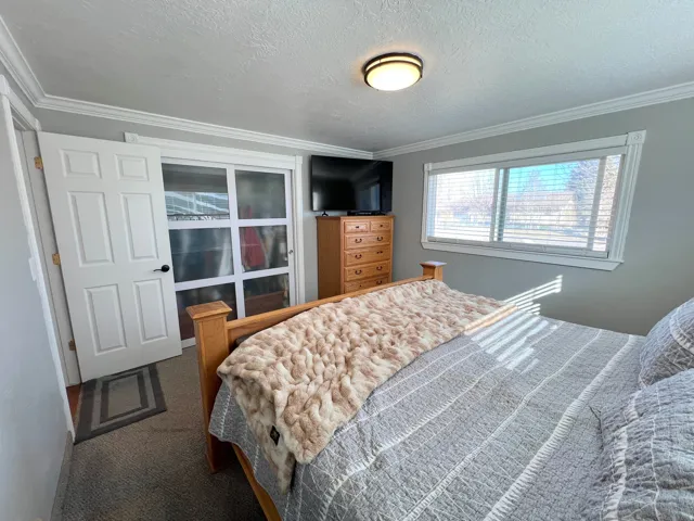 Bedroom with crown molding, a textured ceiling, and dark carpet