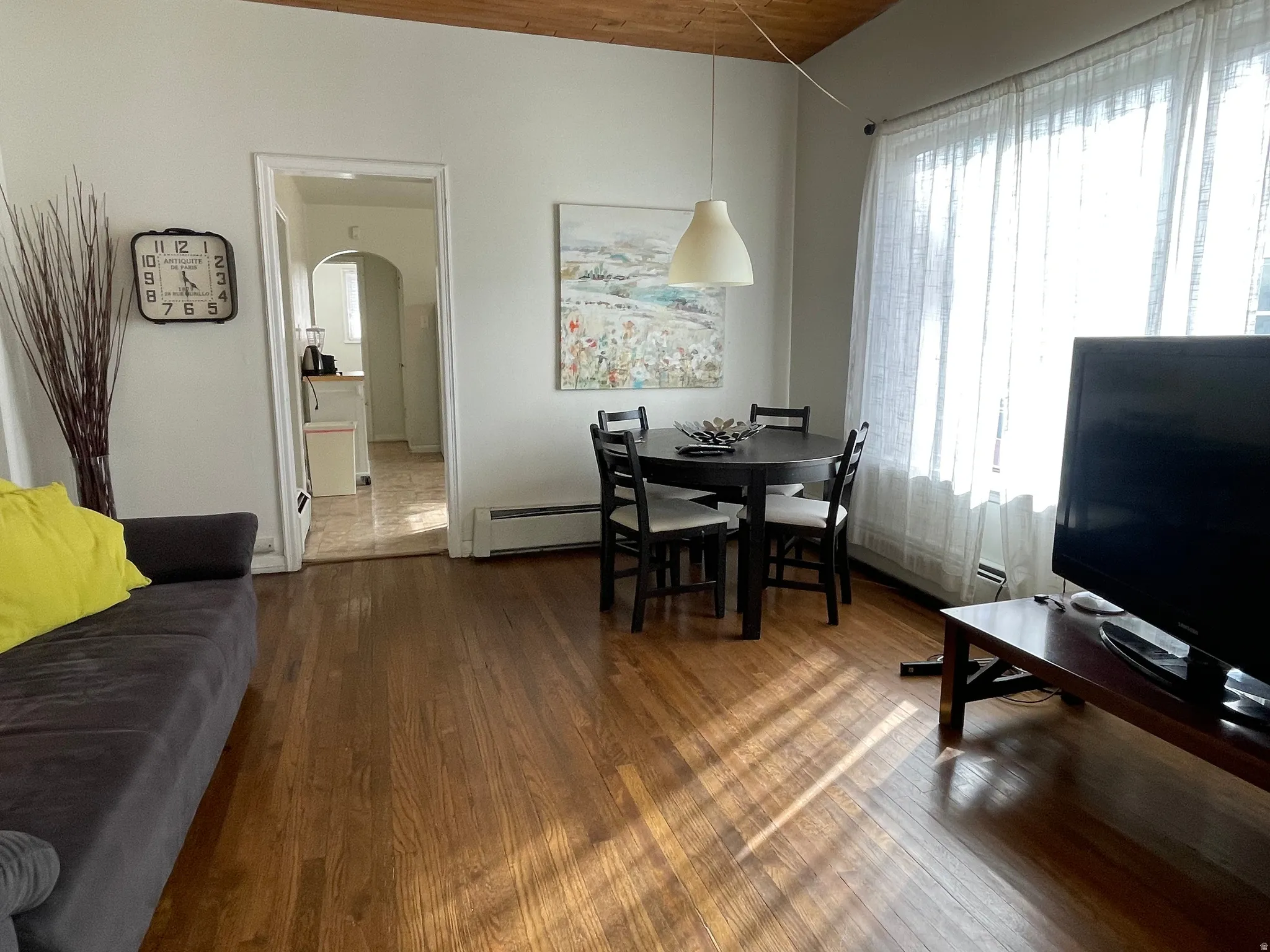 Dining room with arched walkways, dark wood finished floors, and a baseboard heating unit