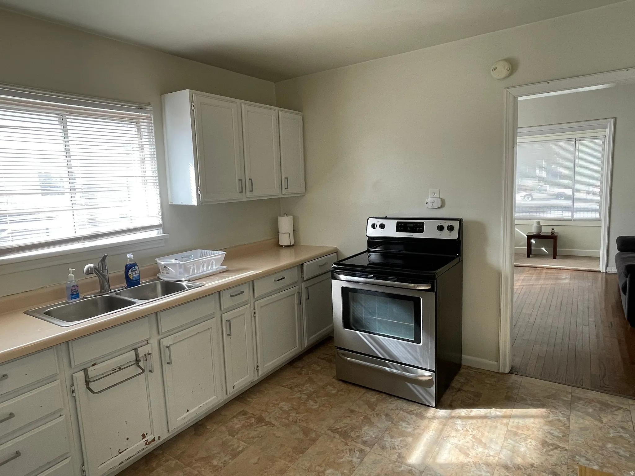 Kitchen with stainless steel electric range oven, light countertops, and white cabinets