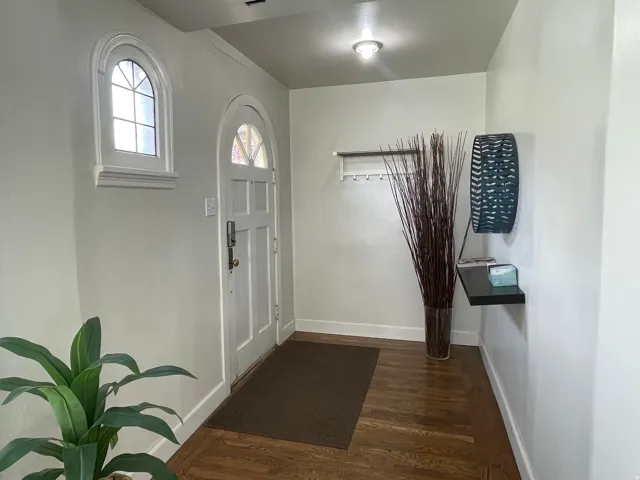 Foyer with dark wood-style flooring and baseboards