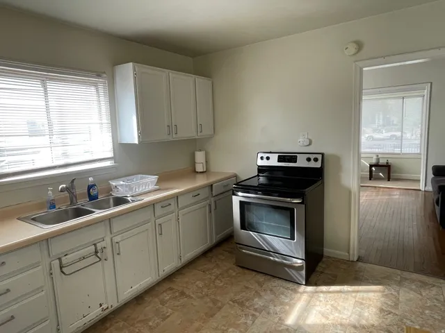 Kitchen with stainless steel electric range oven, light countertops, and white cabinets