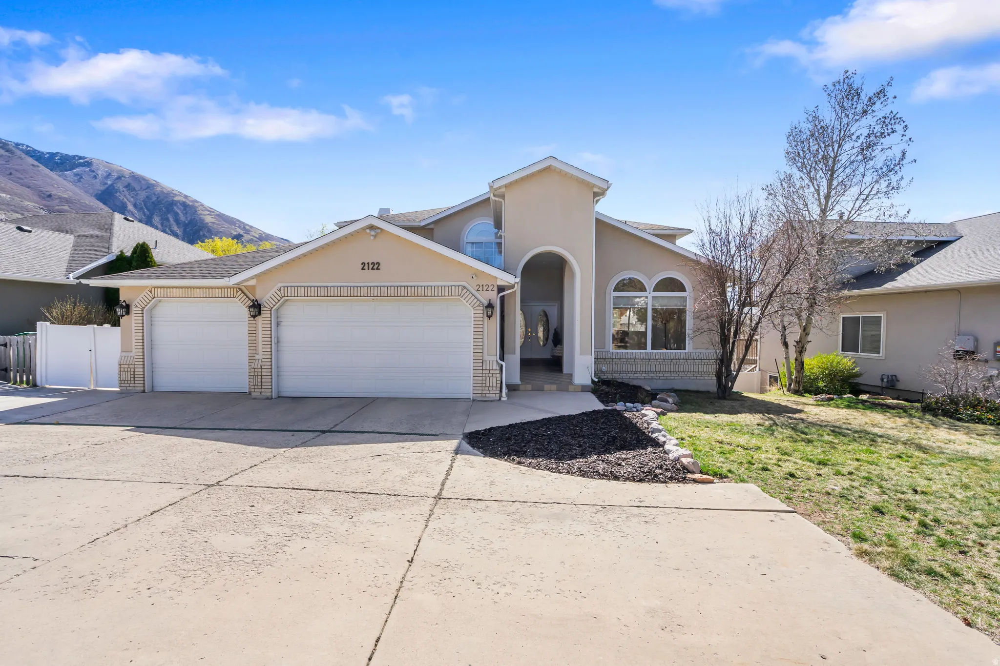 View of front of property featuring an attached garage, concrete driveway, stucco siding, a front lawn, and a mountain view