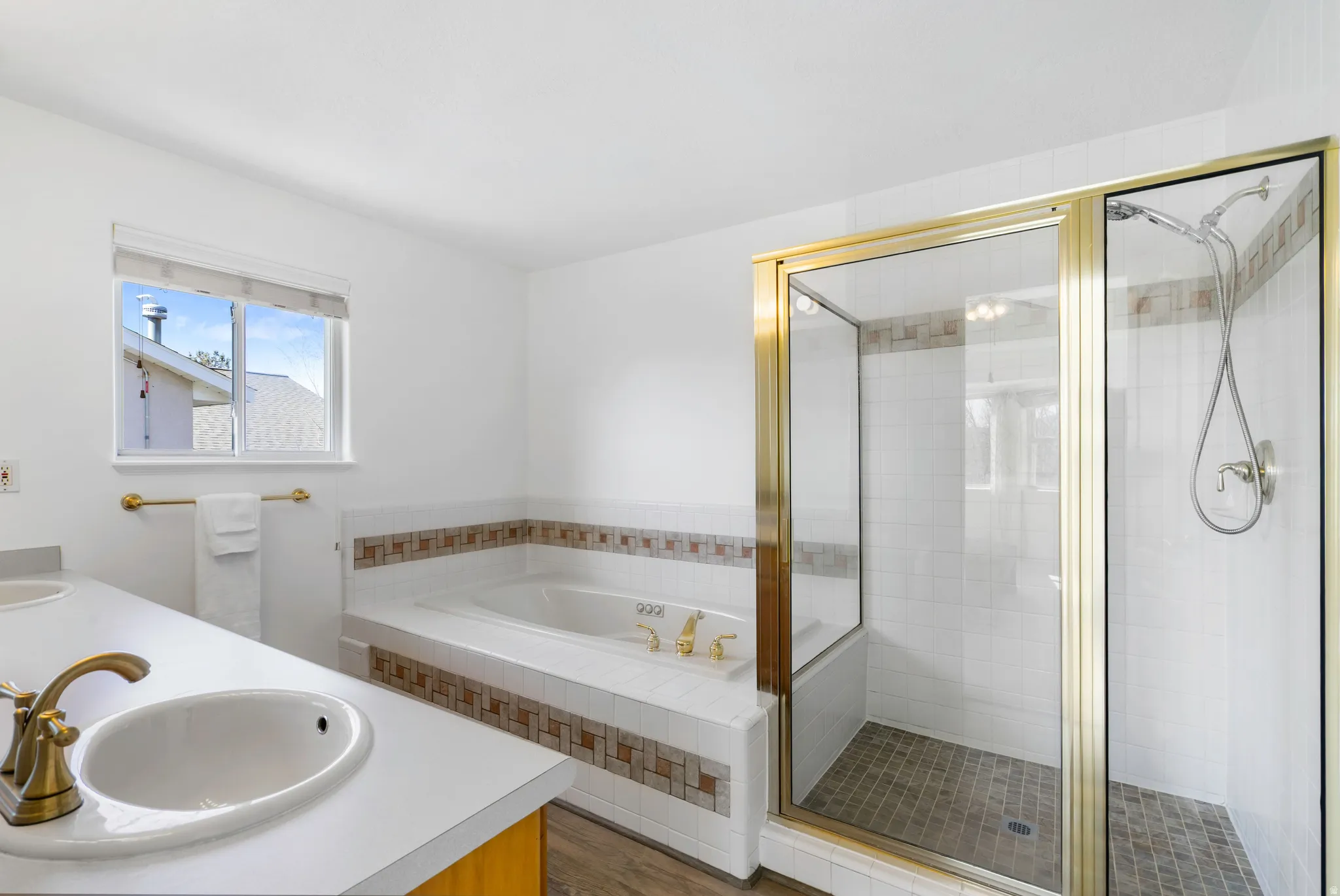 Bathroom featuring double vanity, a garden tub, a shower stall, and dark wood finished floors
