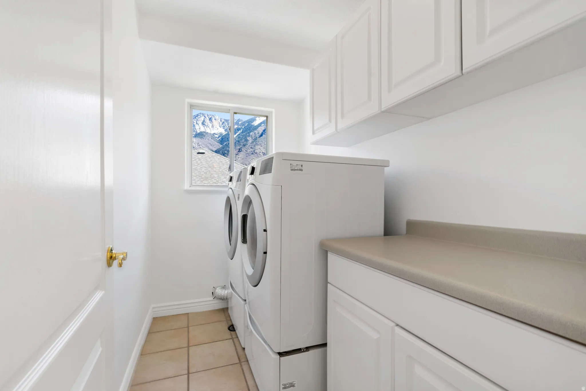 Laundry room with cabinet space, light tile patterned flooring, and independent washer and dryer