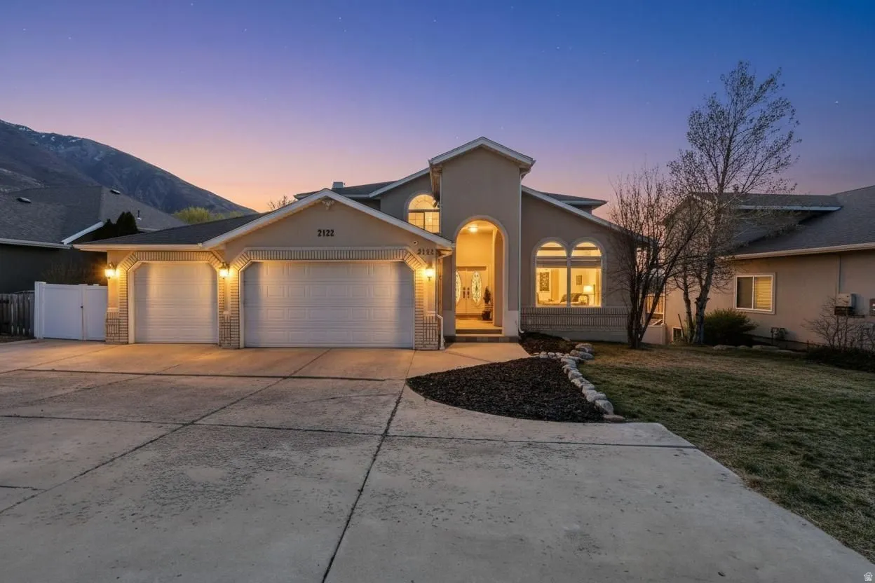 View of front of house featuring a garage, concrete driveway, stucco siding, and a lawn
