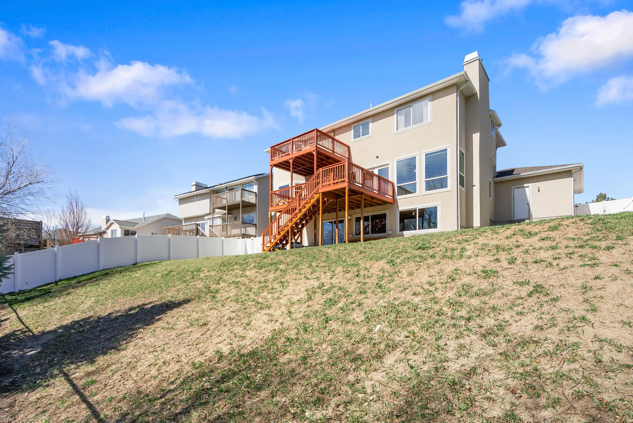 Rear view of house featuring a deck, a chimney, and stucco siding