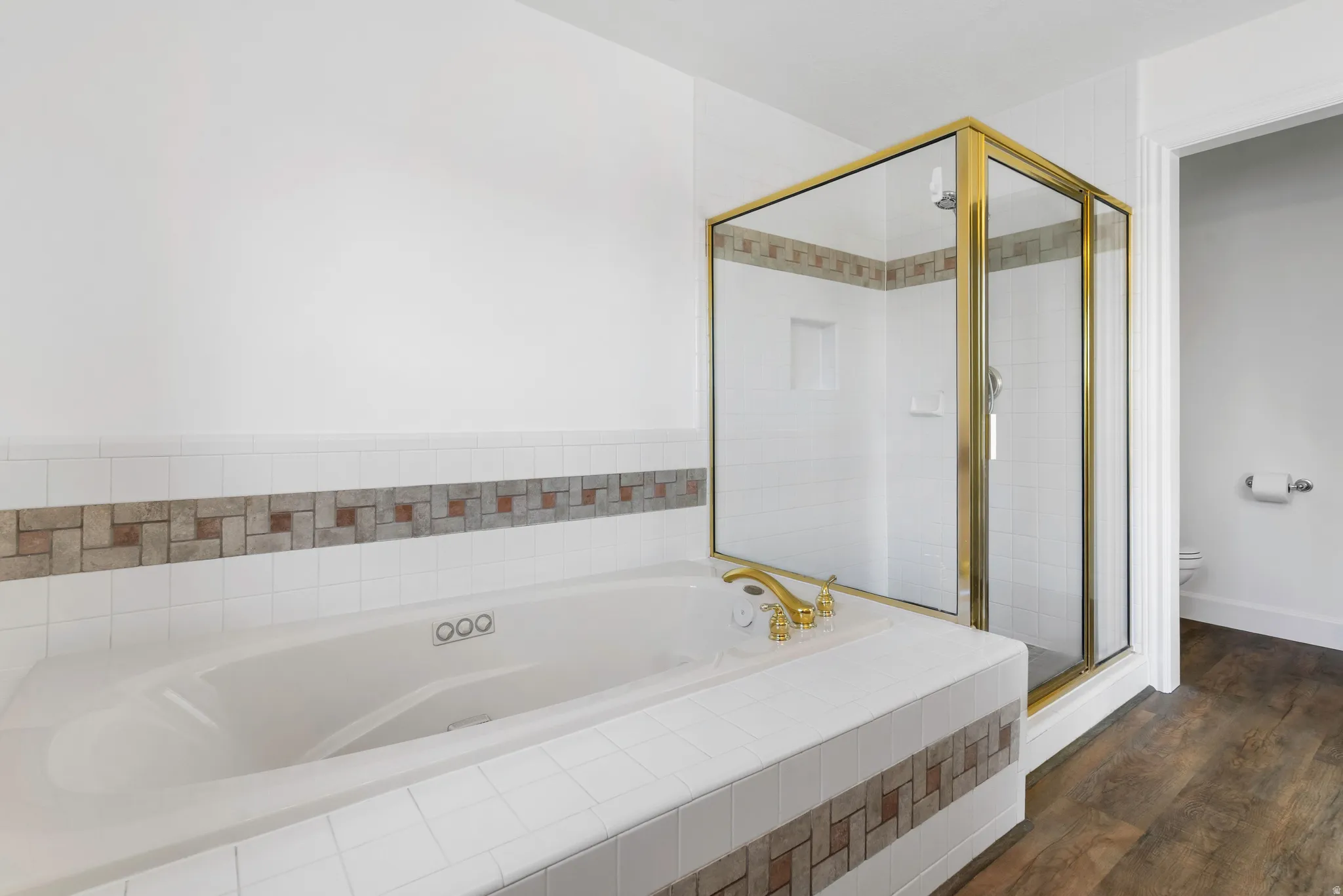 Bathroom with a garden tub, a shower stall, and dark wood finished floors