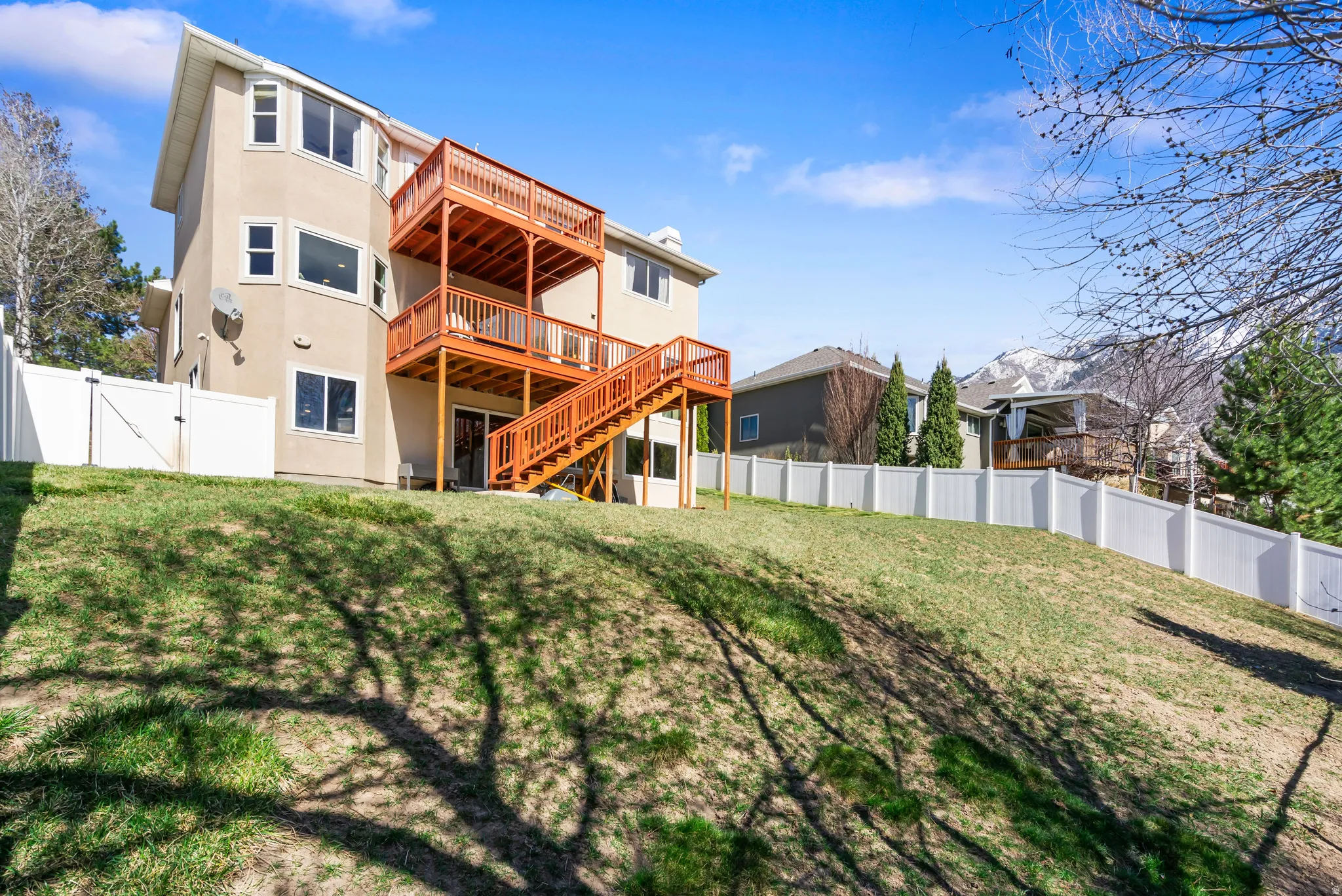Back of house with a fenced backyard, a gate, a wooden deck, stucco siding, and a chimney