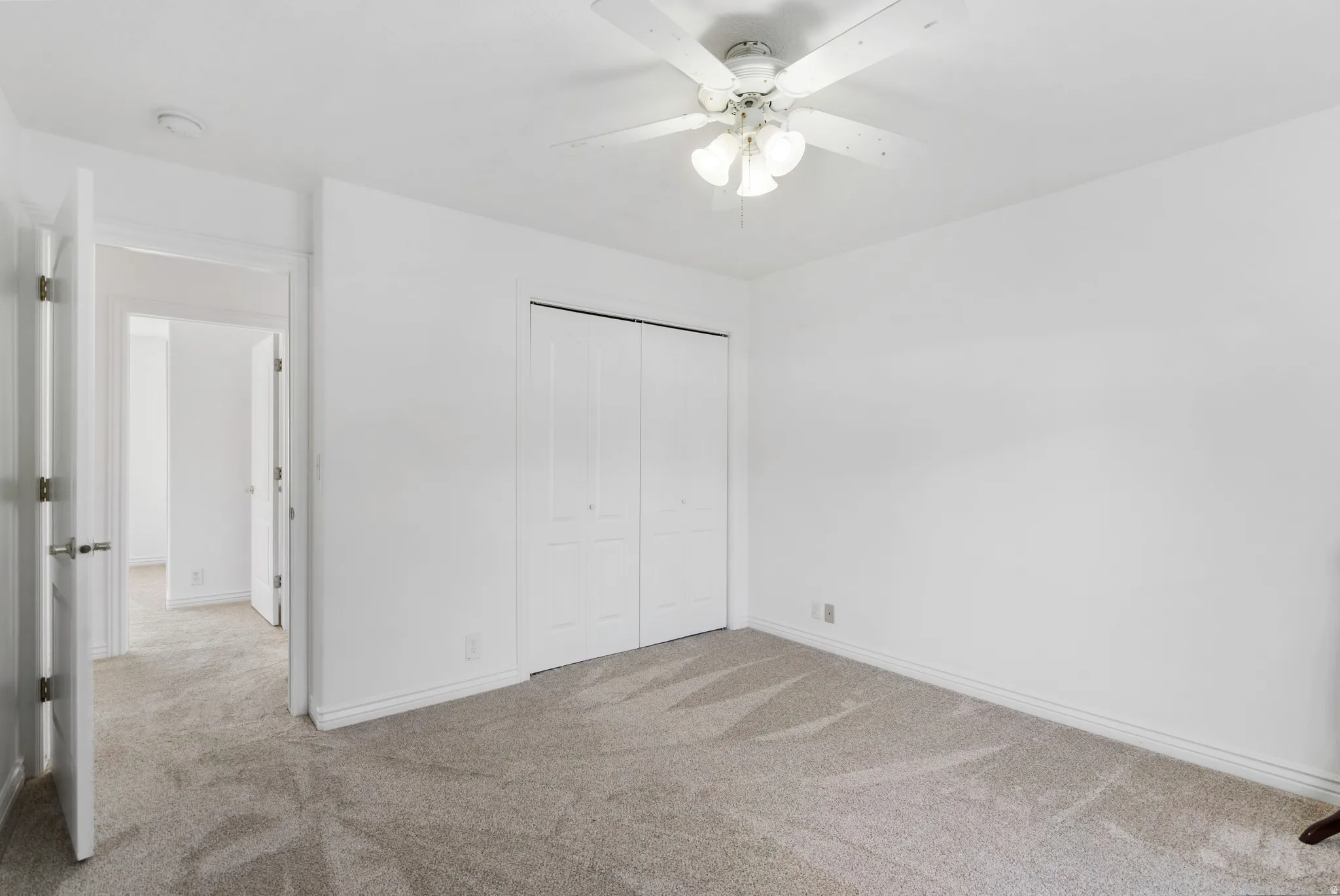 Unfurnished bedroom with light carpet, a closet, and a ceiling fan