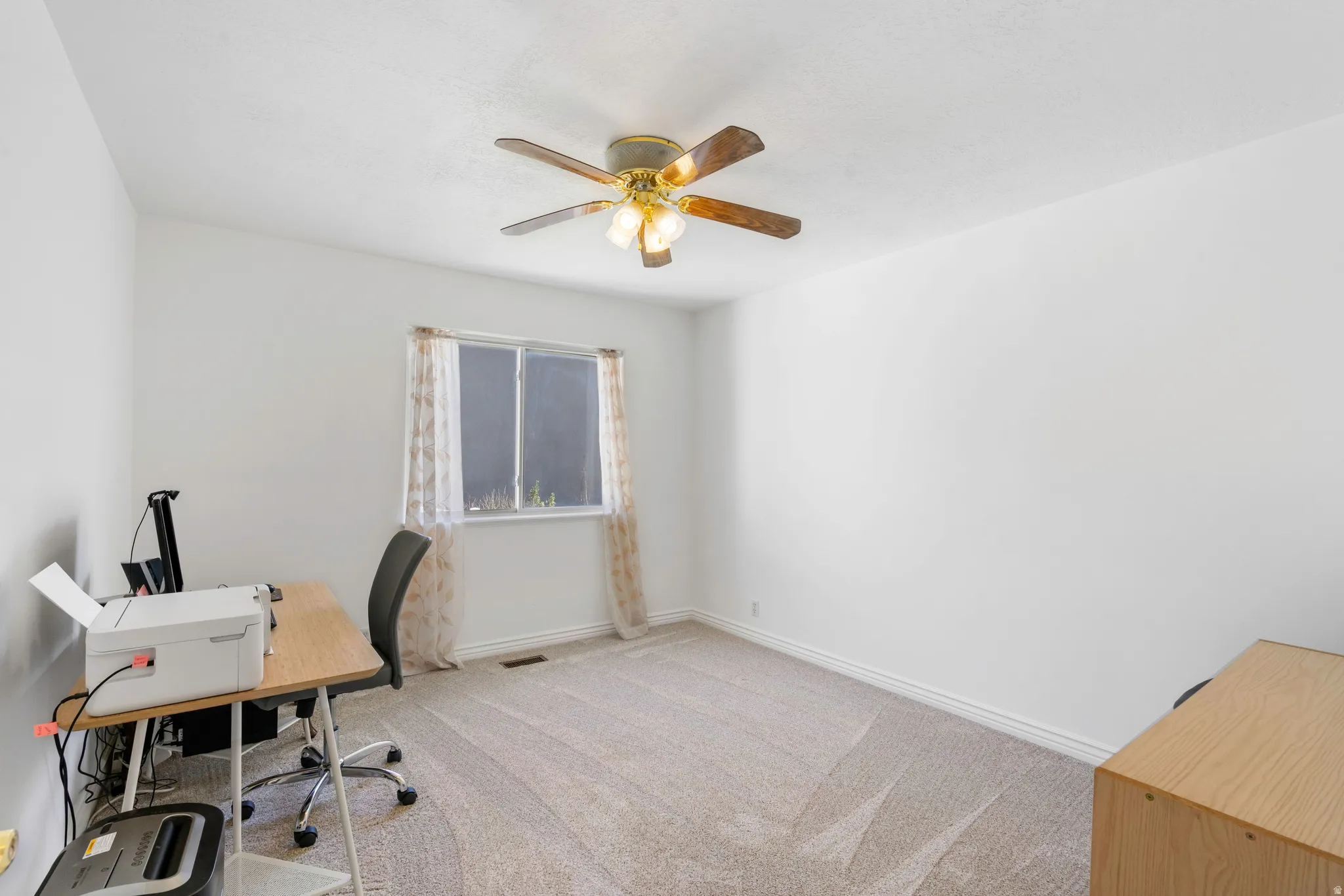 Office space with light colored carpet and a ceiling fan
