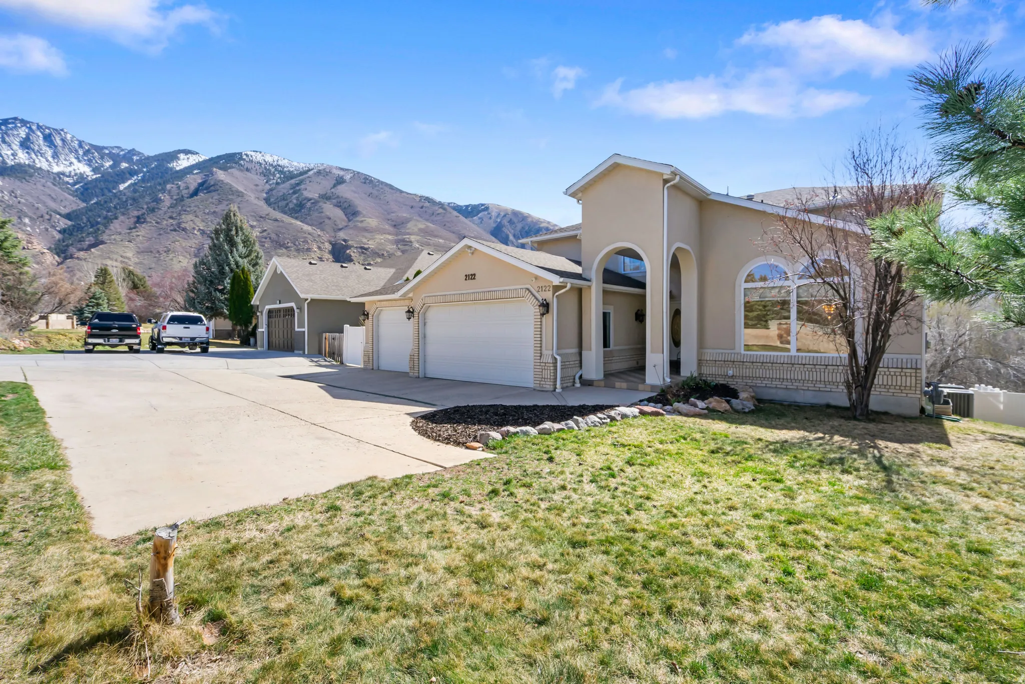 View of front of property featuring stucco siding, concrete driveway, an attached garage, a mountain view, and a front lawn