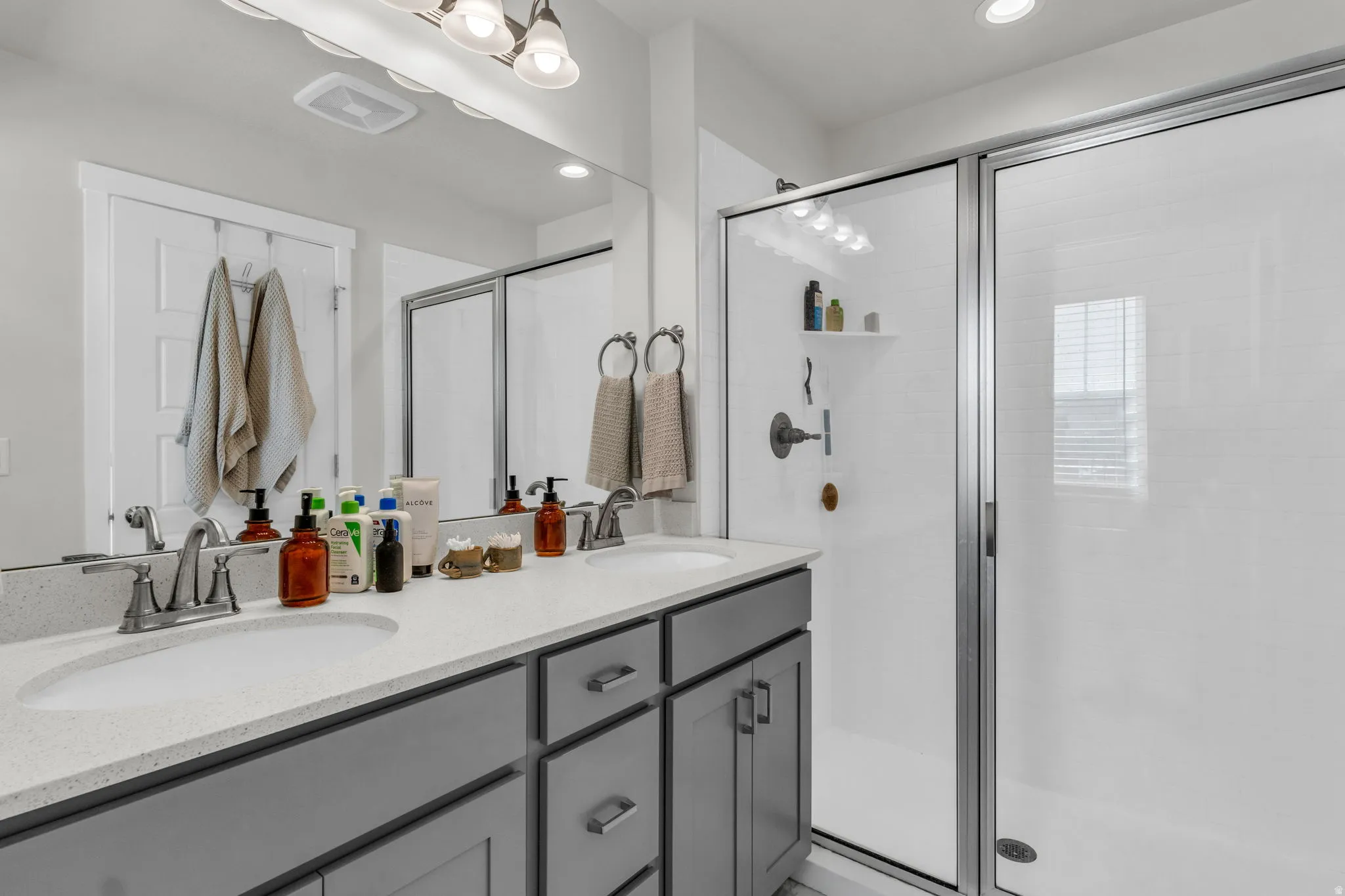 Full bath with double vanity, a stall shower, and recessed lighting