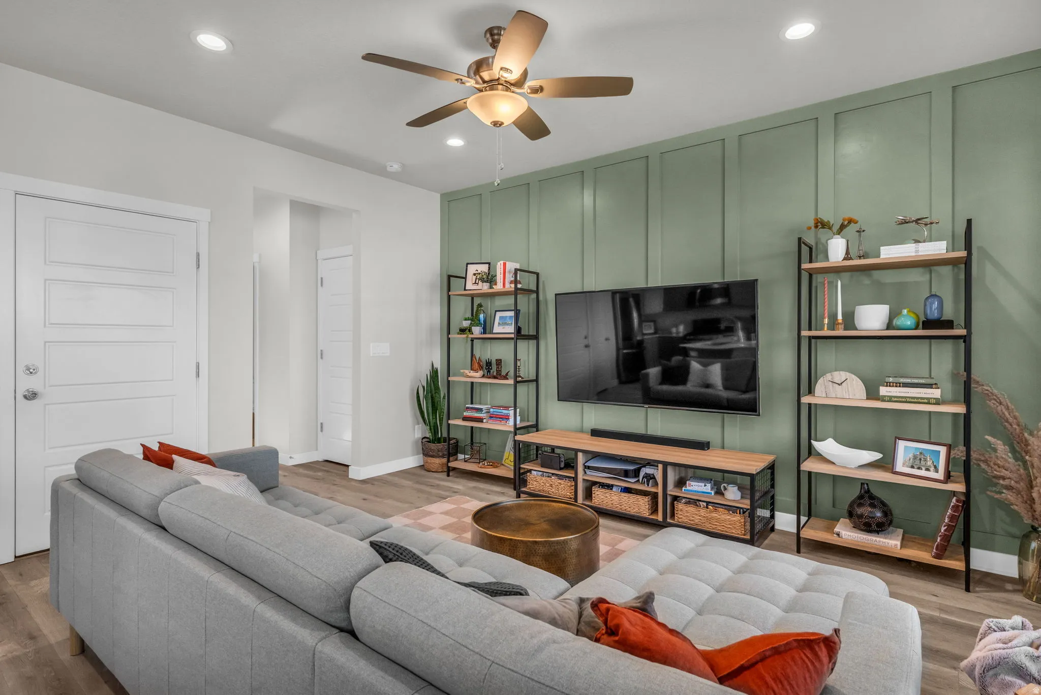 Living area with a decorative wall, ceiling fan, wood finished floors, recessed lighting, and an accent wall