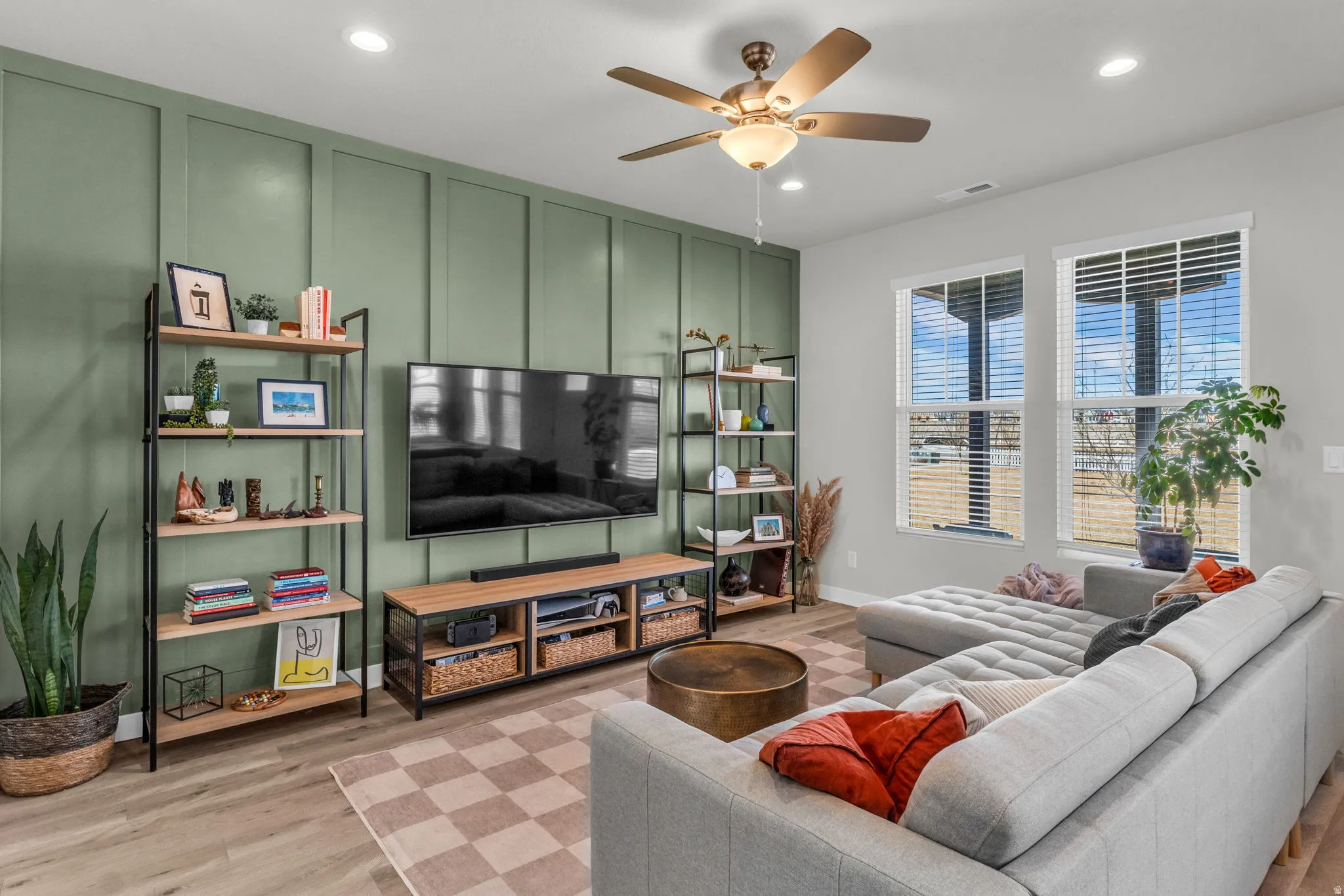 Living area with a decorative wall, ceiling fan, light wood finished floors, and recessed lighting