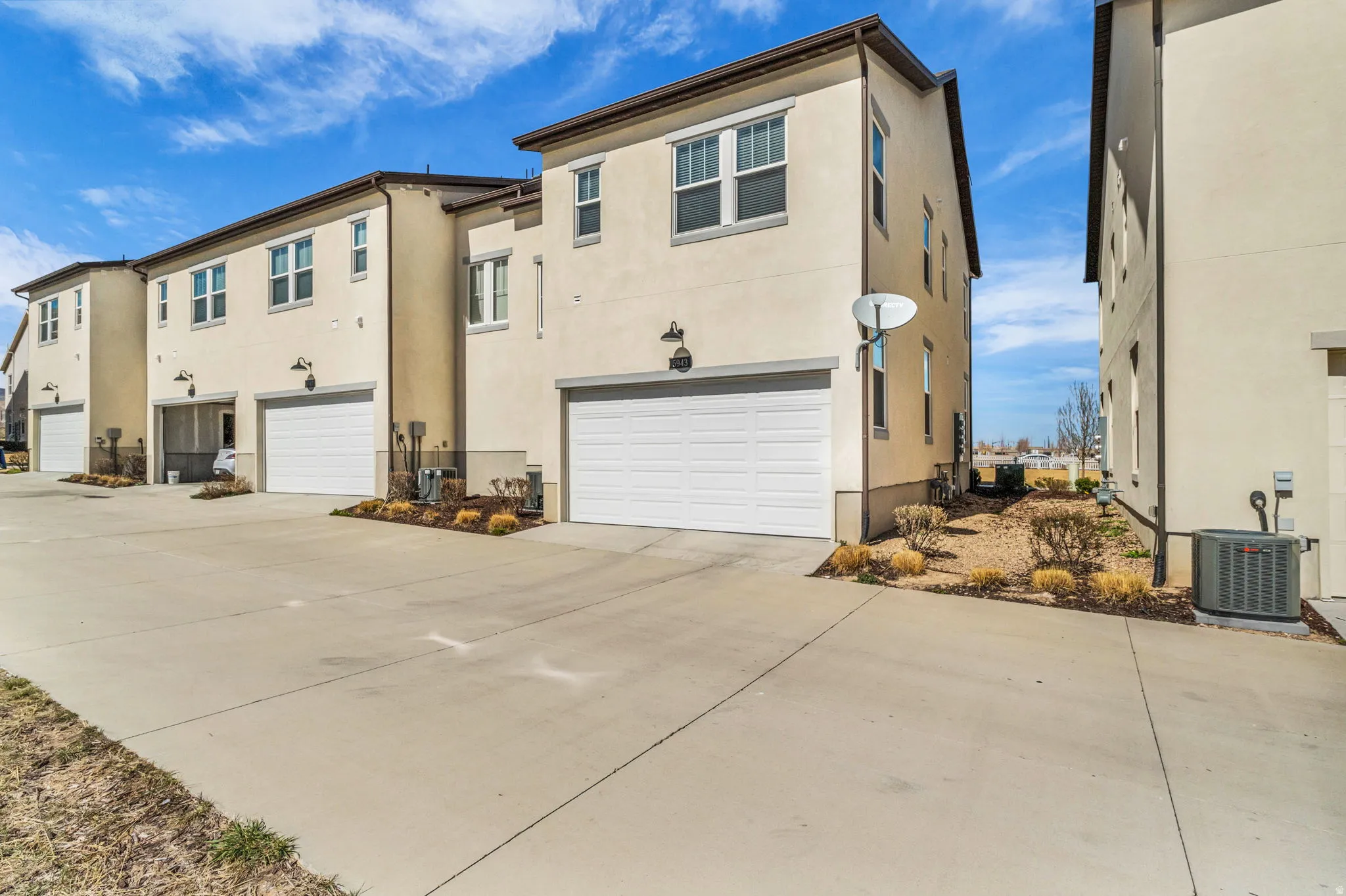 Rear view of house with an attached garage, stucco siding, and driveway