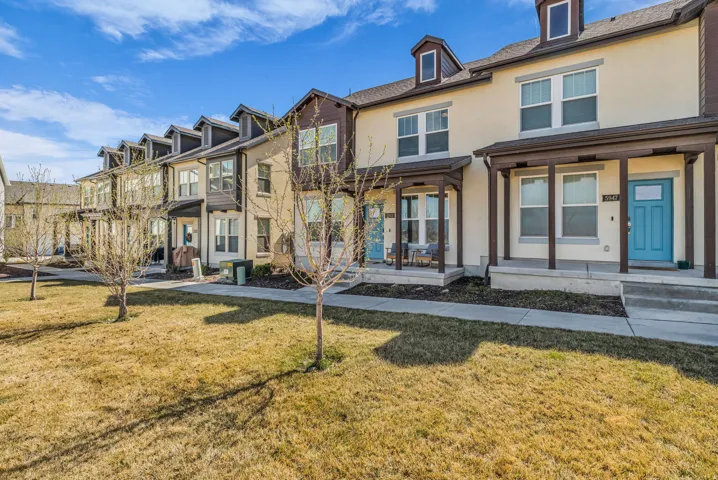 View of front facade featuring stucco siding, covered porch, and a front yard