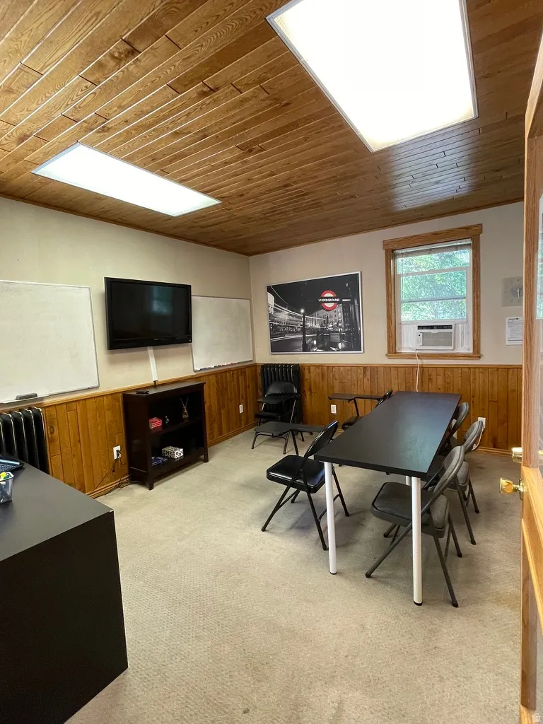 Game room with wooden walls, wainscoting, wood ceiling, radiator, and cooling unit