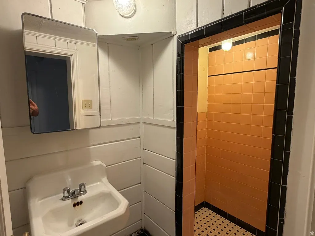 Tile shower enclosure with black trim, ceramic wall tiles, and mosaic floor tiles