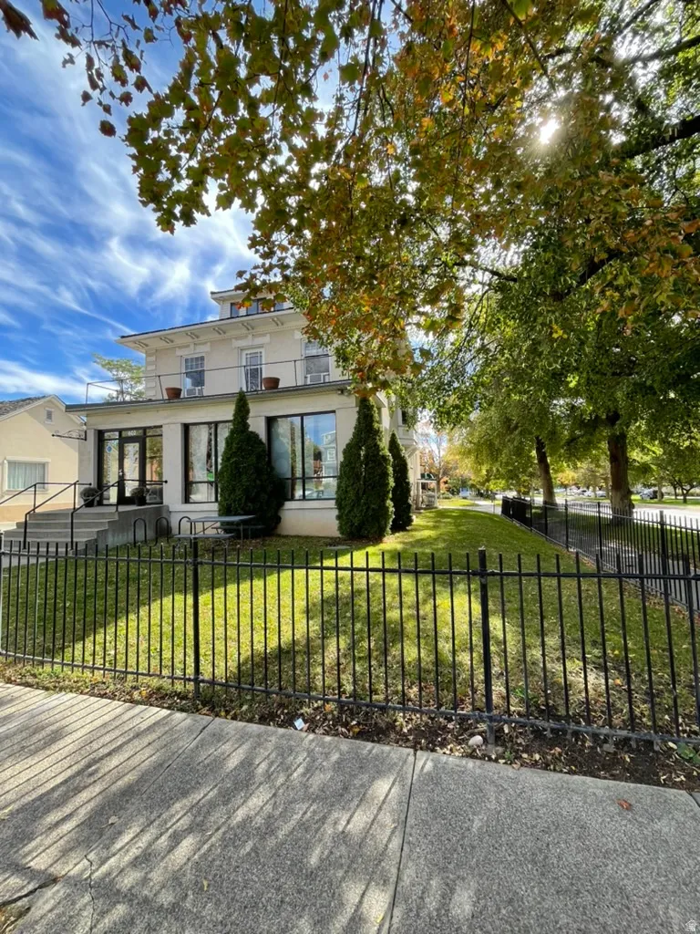 Italianate-style house featuring a fenced front yard, stucco siding, and a patio area