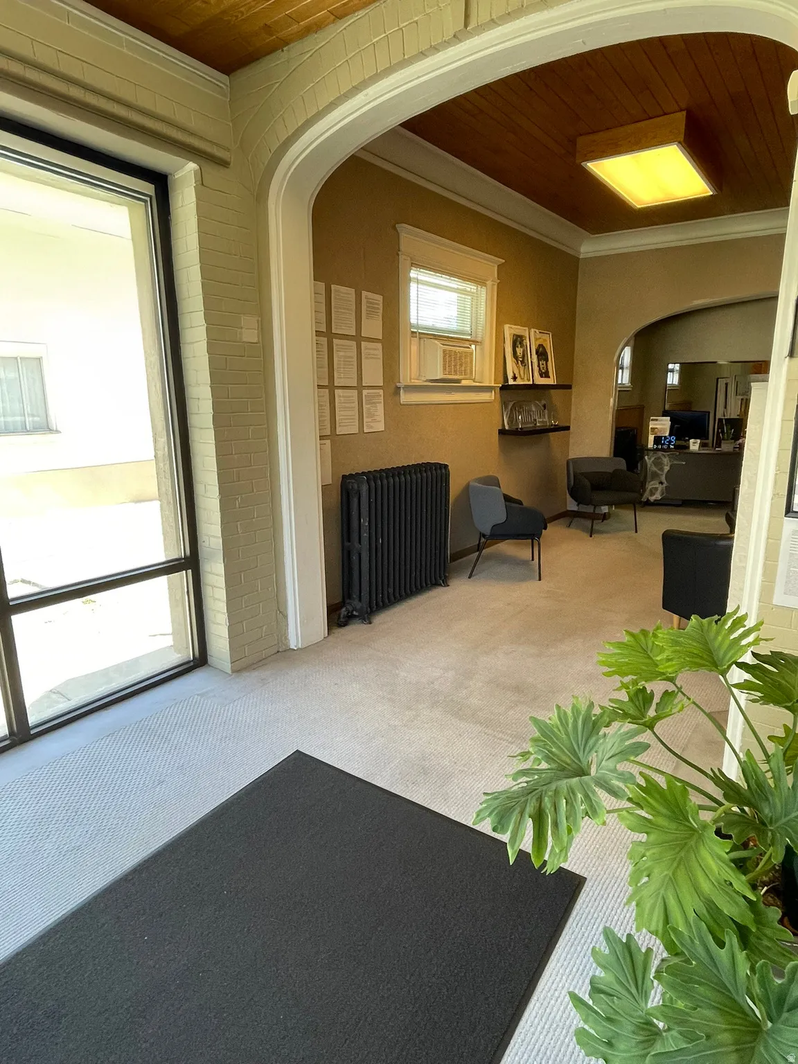 Community lobby with wooden ceiling, ornamental molding, and brick wall