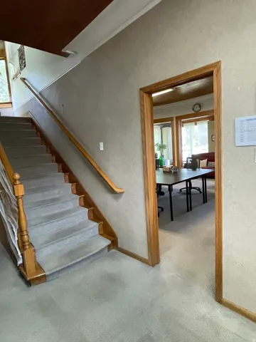 Stairs with a textured wall, crown molding, and carpet flooring